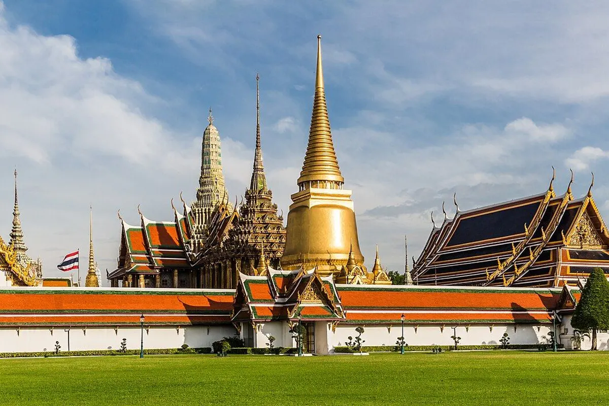 The golden chedi and orange-and-green tiled roofs of Wat Phra Kaew seen from the Grand Palace's outer court.