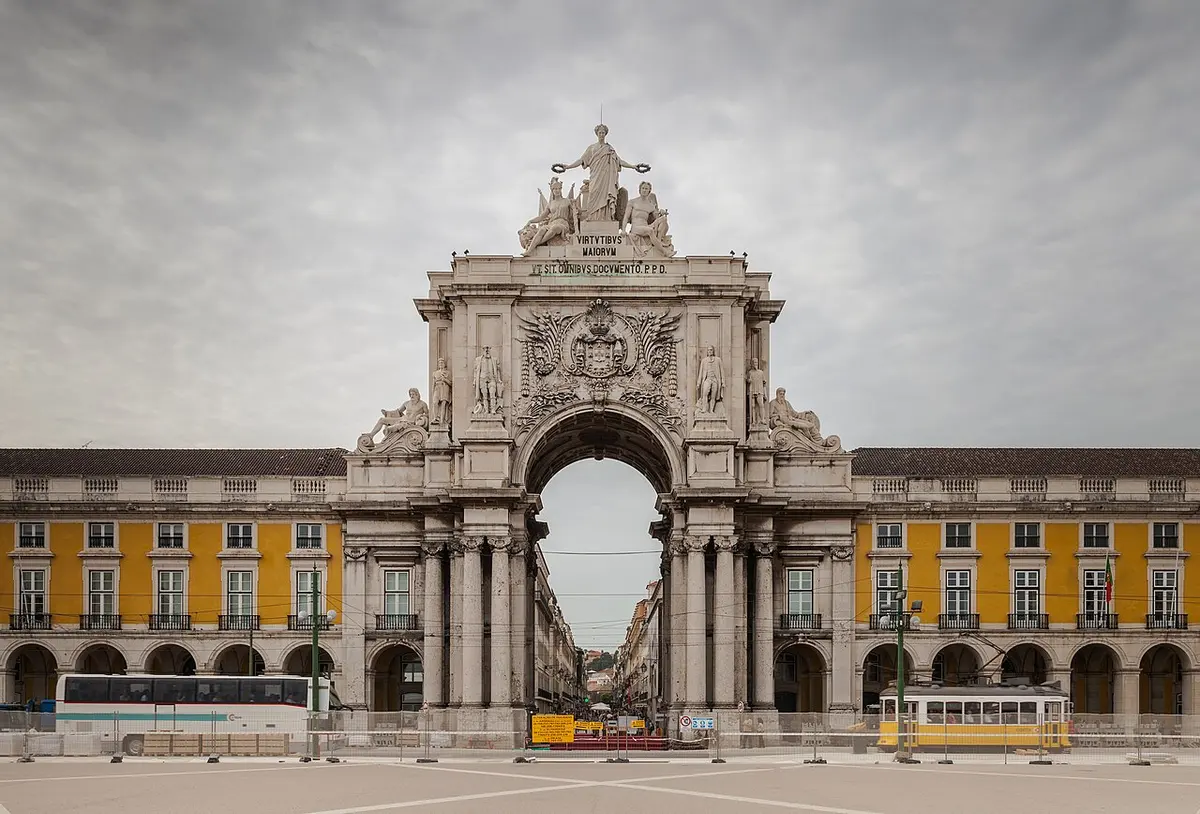 The Rua Augusta Arch on Praça do Comércio with a yellow tram passing in front