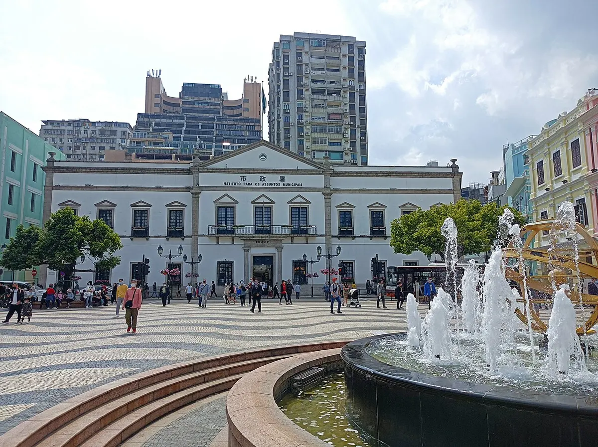 波浪纹碎石铺地的广场与喷泉,后方是白色新古典主义市政建筑