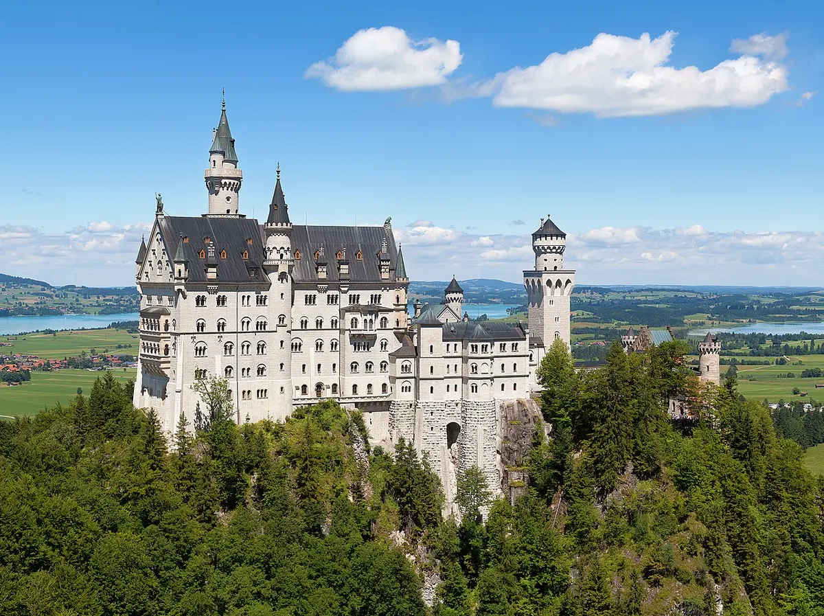 Neuschwanstein Castle among forest and mountains, seen from the Marienbrücke