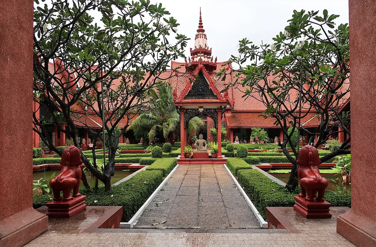 The courtyard garden of the National Museum of Cambodia framed by red Khmer-style roofs.