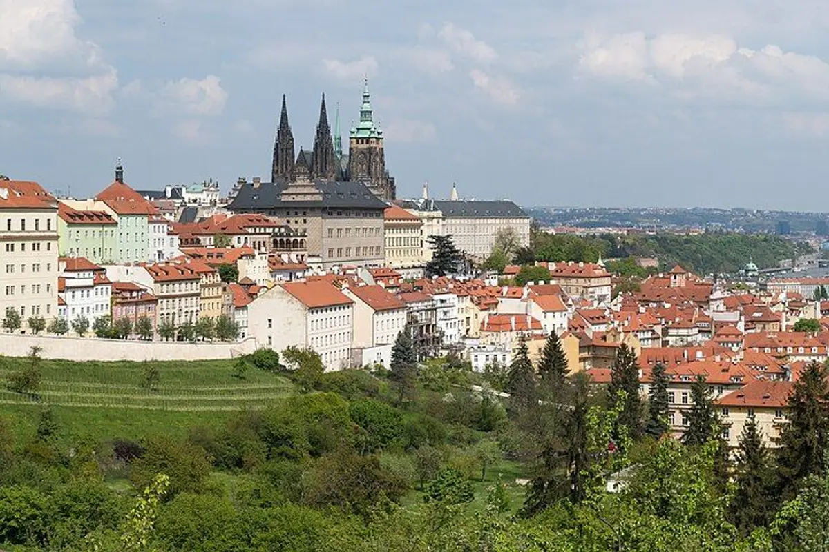 St. Vitus Cathedral and red rooftops beyond a hillside of fresh spring green.