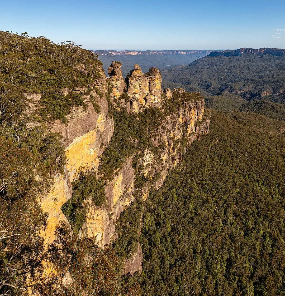 The Three Sisters rock formation rising above the forested valley in the Blue Mountains