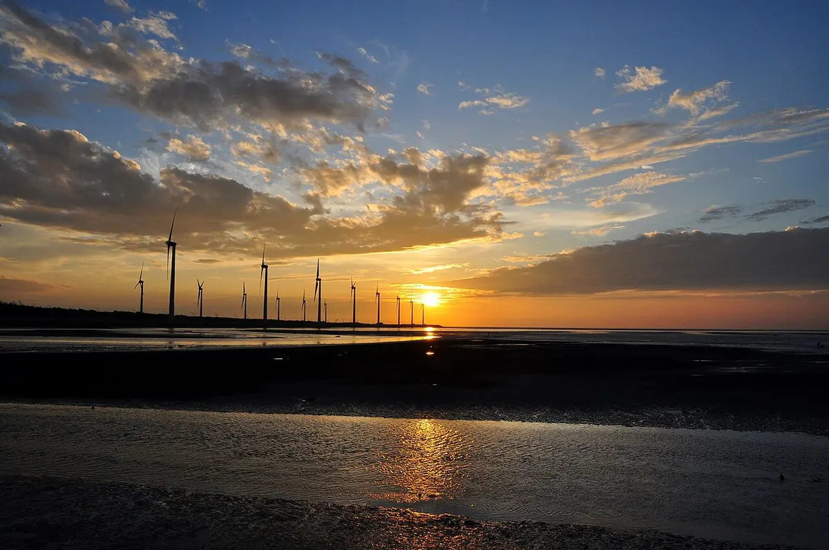 Gaomei Wetlands with a row of wind turbines under a cloudy sunset sky