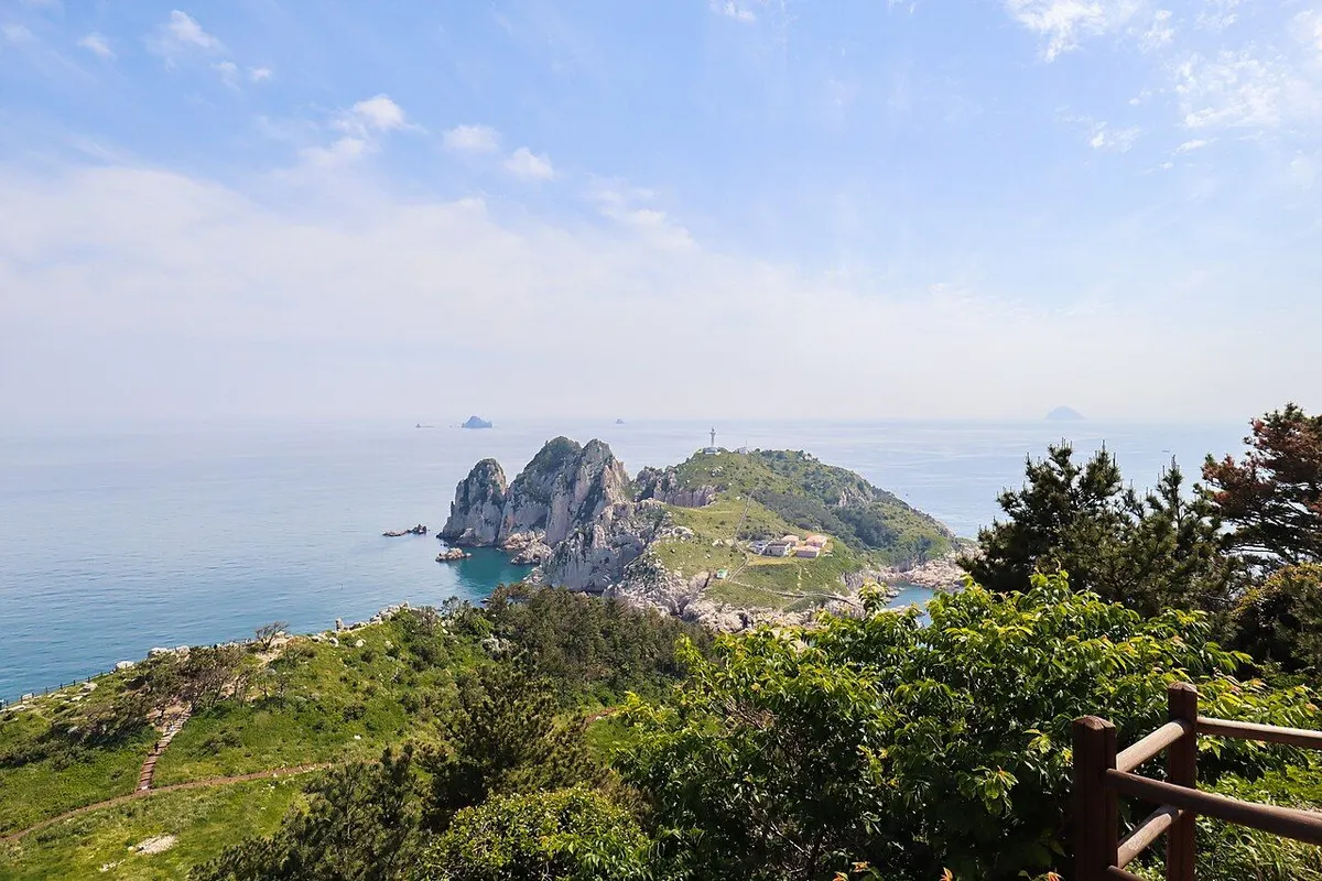 小每勿島から見下ろした灯台島の岩壁と白い灯台。