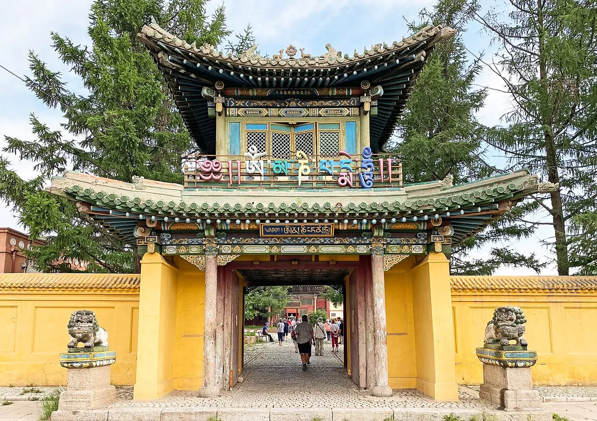 绿色瓦顶、黄色院墙的寺门，两侧立着石狮，游客正穿门走向院内