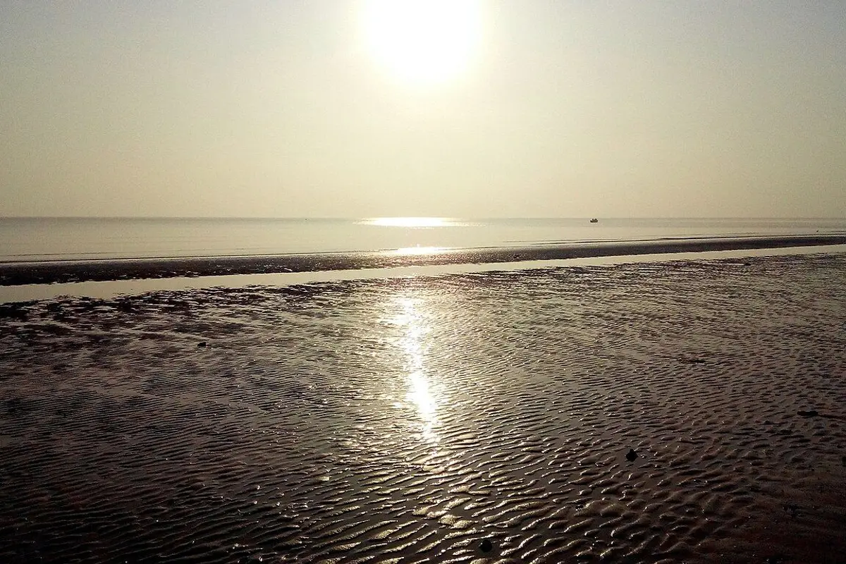 朝日が波紋模様の砂浜と穏やかな海を照らす煙台の海岸。