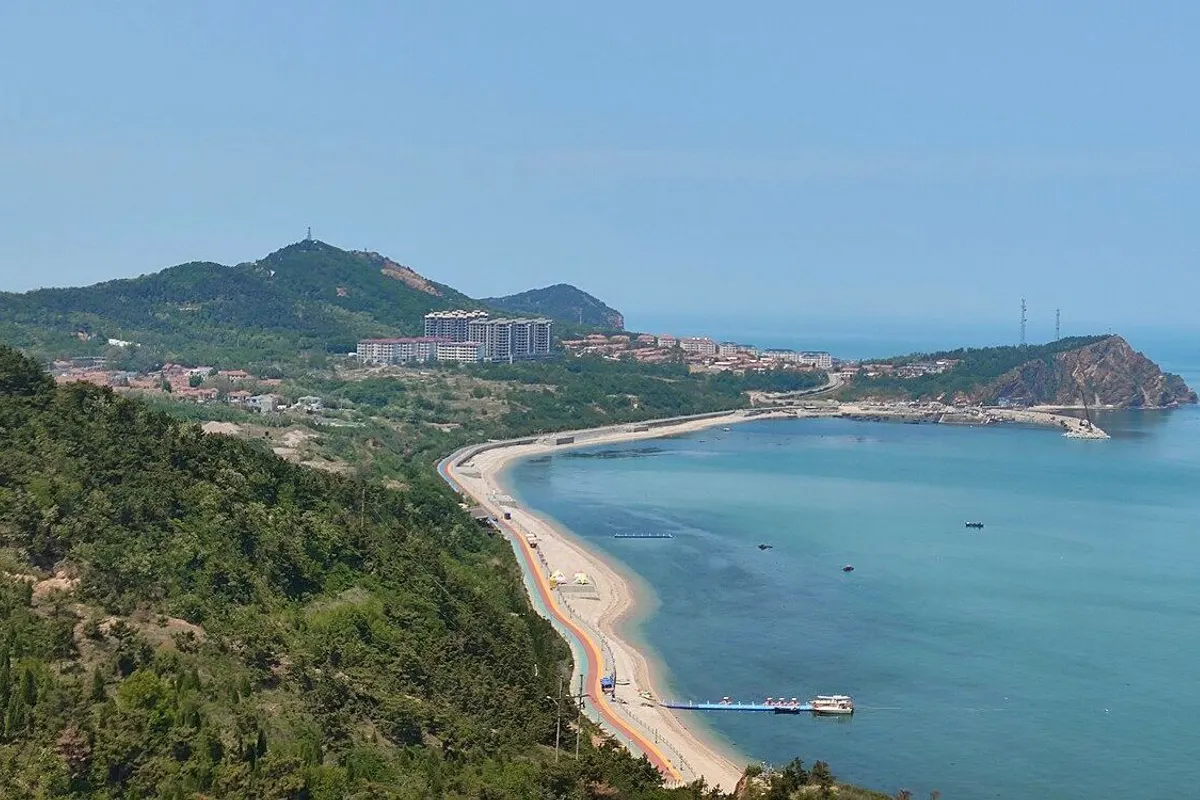 緑の山並みの下に弧を描く砂浜とターコイズ色の海が広がる長島の南長山島。