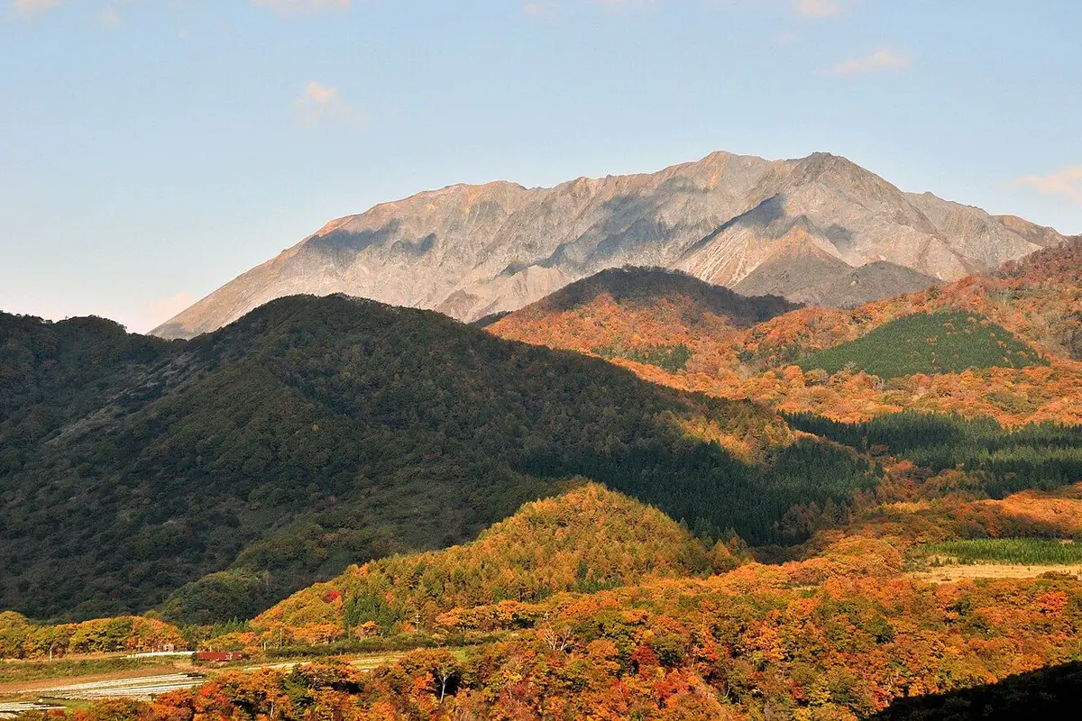 Mt. Daisen's bare rocky ridge rising above slopes covered in autumn colours.