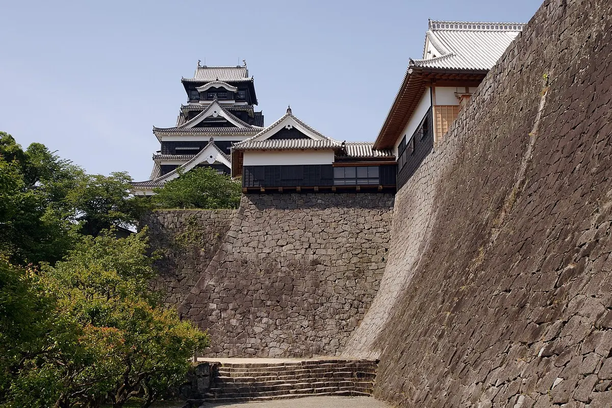 Kumamoto Castle's keep above its tall curved stone walls.