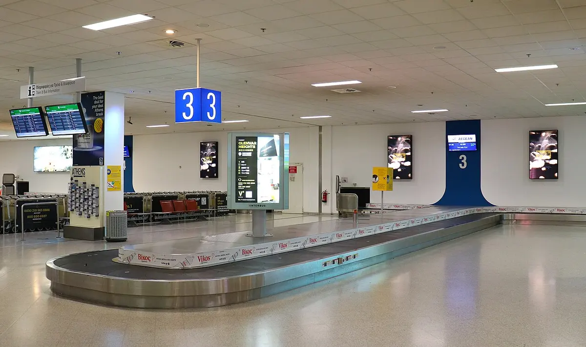 공항 수하물 찾는 곳의 컨베이어 벨트 위로 여행 가방들이 돌고 있다.