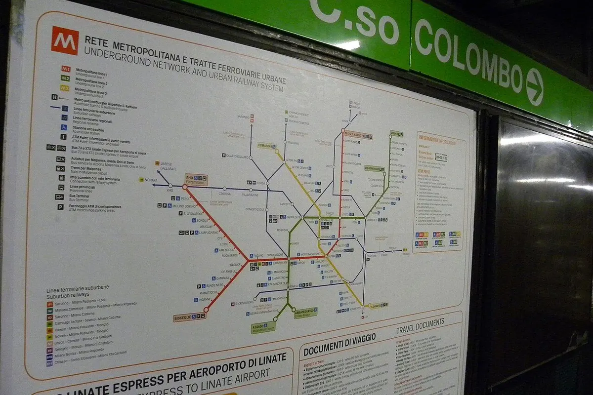 A metro network map on a station wall, next to a station sign.