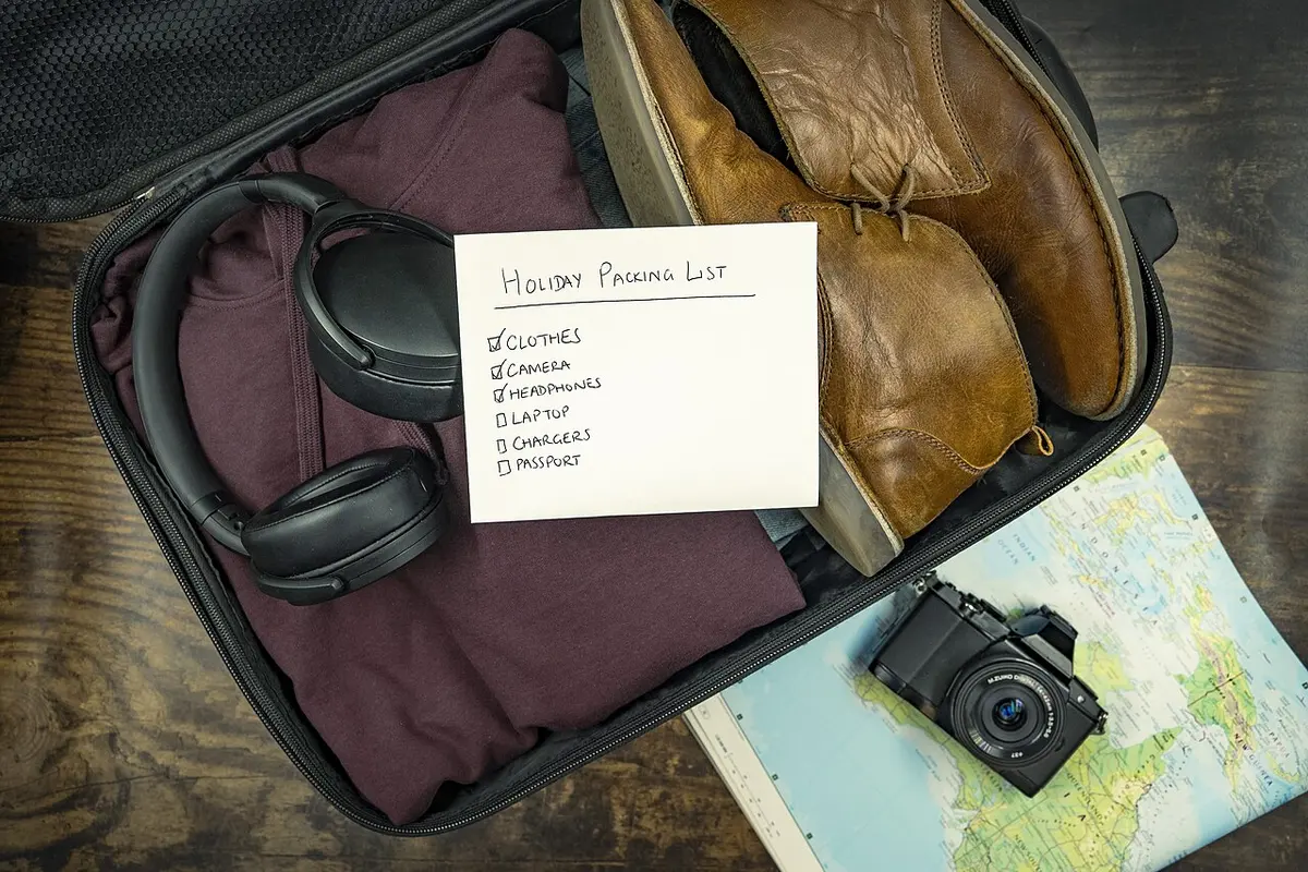 An open suitcase packed with travel essentials, with a map and a camera beside it.